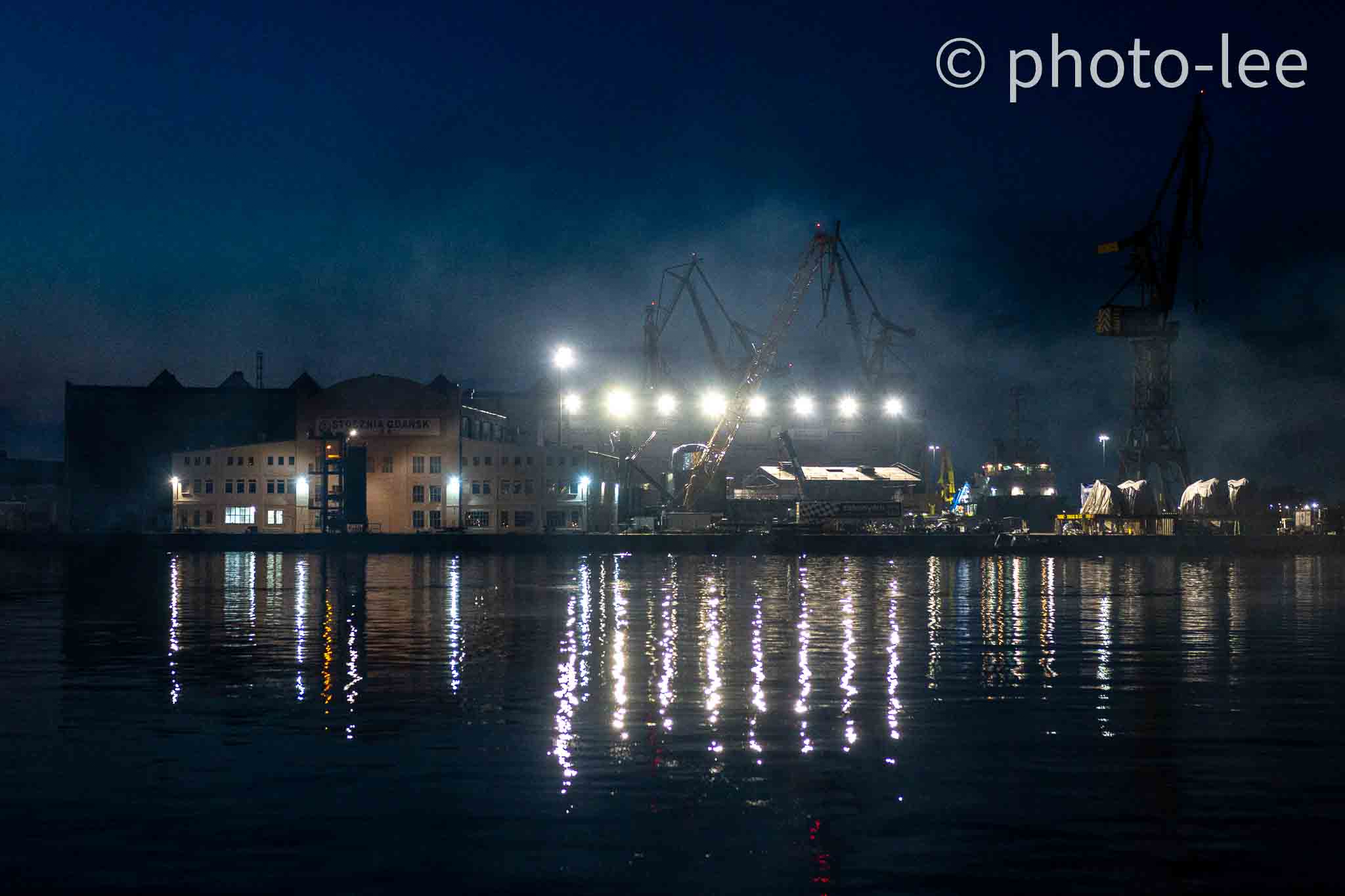 Nebel lässt die Scheinwerfer am Hafen verstreuter auftrahlen